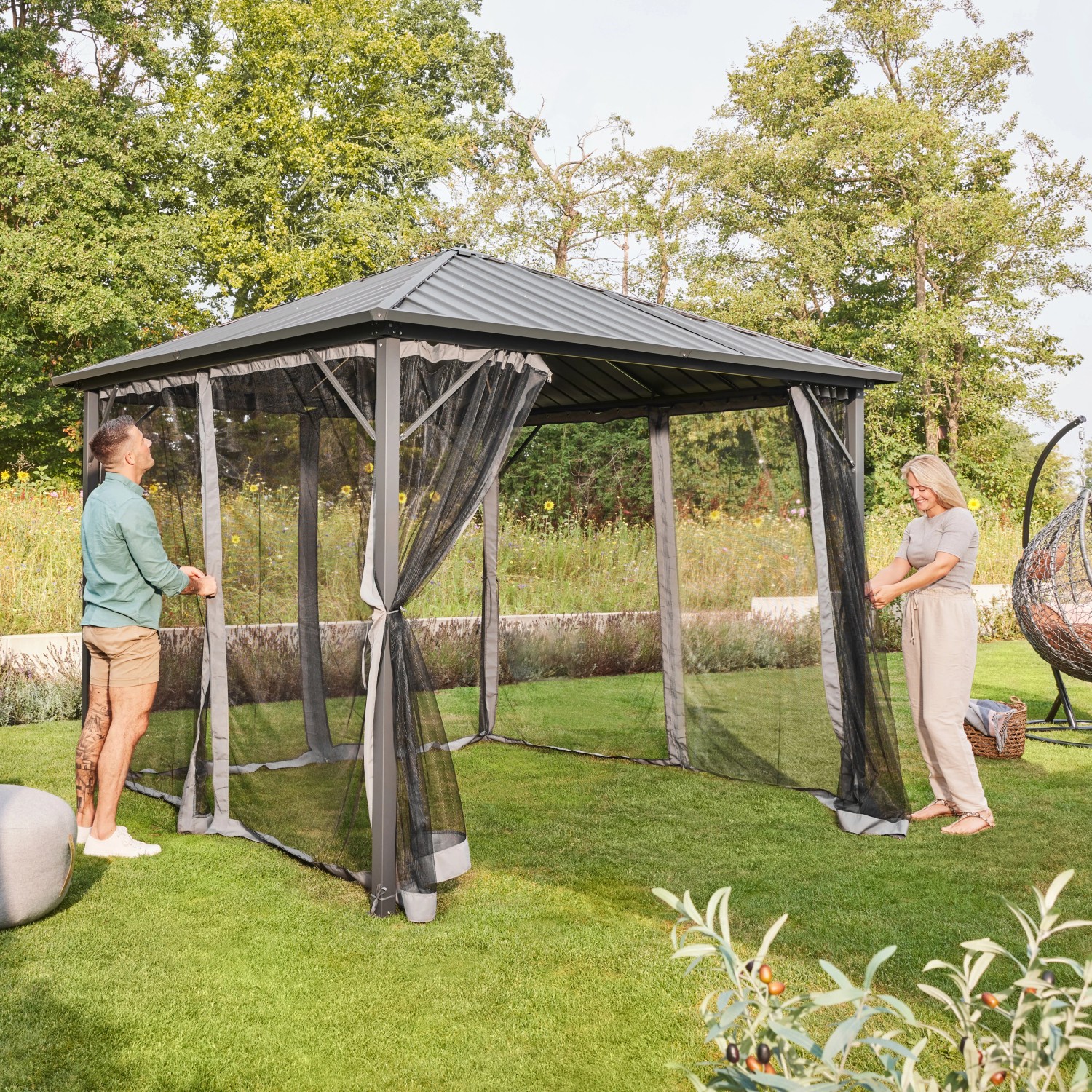 Home Deluxe Pavillon Azur mit Solar-LED und Moskitonetz im Garten, Personen öffnen Seitenteile.