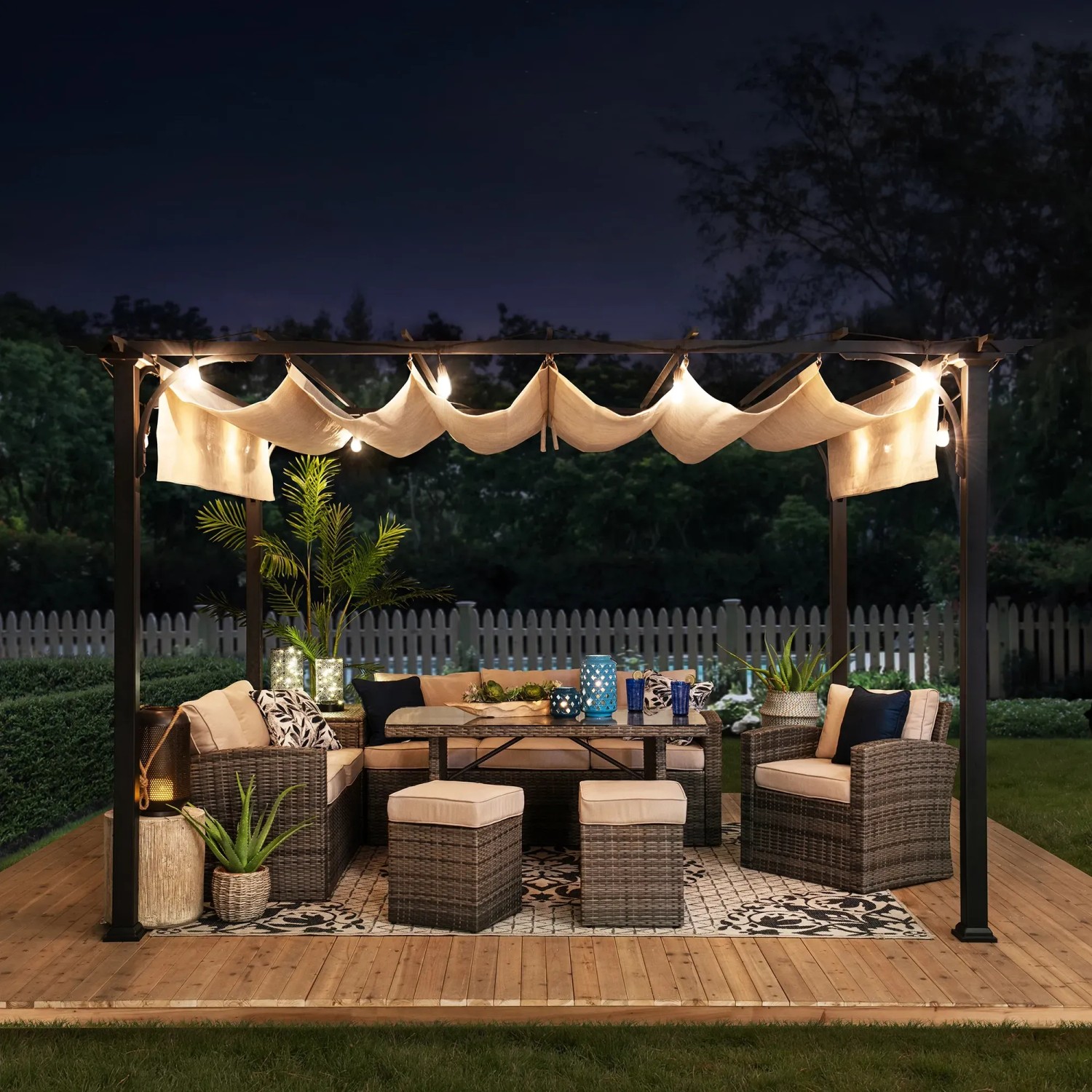 Weiße Sunjoy Pergola Giona aus Stahl (363x277cm) mit beigem Stoffdach und Gartenmöbeln auf einer Holzterrasse.