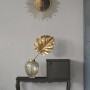 Beige Vliestapete Uni (FSC®) an grauer Wand mit Deko-Elementen wie Spiegel und Vase.