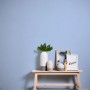 Himmelblaue Vliestapete Uni im Kinderzimmer, kombiniert mit Deko-Elementen auf einem Holzbänkchen.