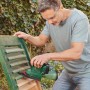 Mann schleift grüne Holzjalousie mit Bosch Akku-Multischleifer UniversalSander 18V-10. Kabelloser Deltaschleifer für vielseitige Schleifarbeiten.