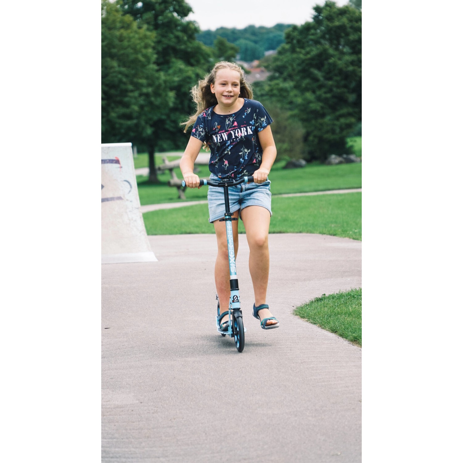 Mädchen fährt hellblauen Six Degrees Aluminium Scooter im Skatepark. Höhenverstellbarer Tretroller mit Klappmechanismus.