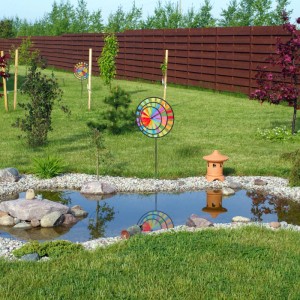 Buntes Relaxdays Windrad 2er Set als Gartendeko im Garten mit Teich.