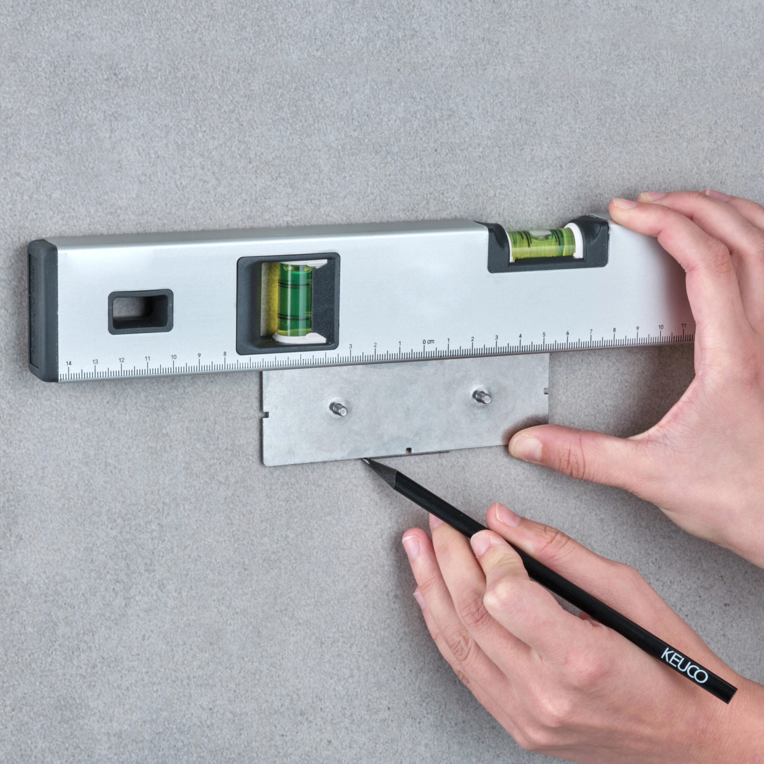 Montage des Keuco Klebe-Sets für Edition 11 Duschkörbe mit Wasserwaage und Bleistift an der Wand.