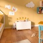Kinderzimmer mit hafergelber Wandfarbe, Spielzeugkiste und Wolkenlampe.