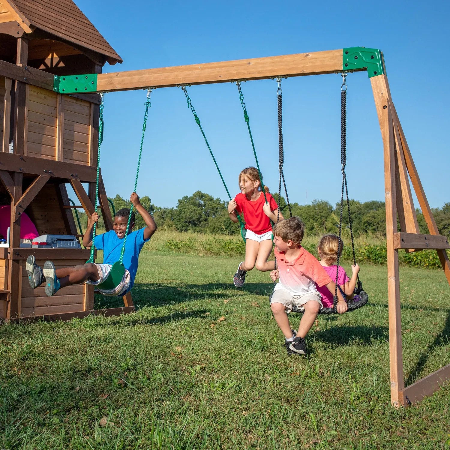 Kinder spielen auf dem Backyard Discovery Spielturm Cedar Cove mit Schaukeln und Rutsche.