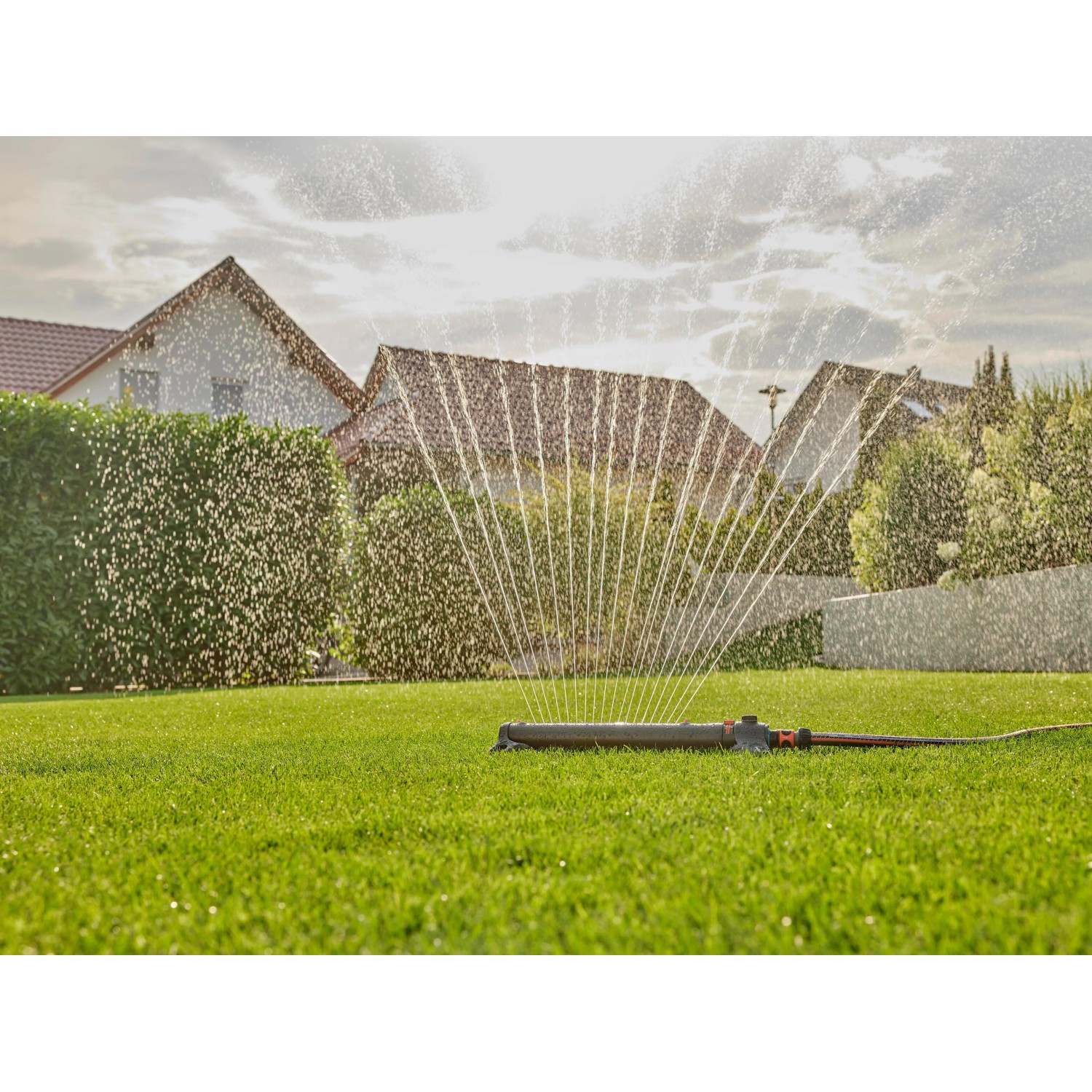 Gardena Viereckregner AquaZoom L bewässert Rasenfläche. Wasserstrahlen im Garten.