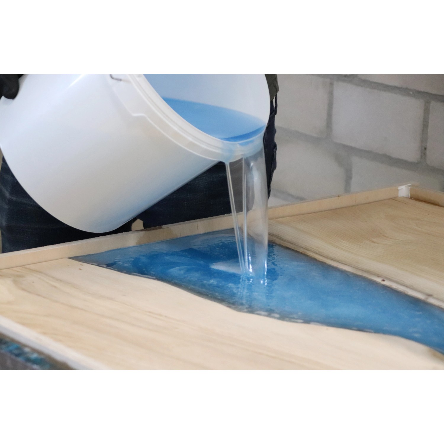 Gießen von blauem CreativEpoxy Epoxidharz in eine Holzform. Spezialspachtel für kreative Projekte.
