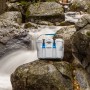Graue Lifetime Kühlbox (26,5L) mit blauem Griff und Verschlüssen vor Wasserfall.