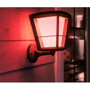 Stehende Philips Hue Econic LED-Laternenleuchte mit farbigem Licht an Hauswand.