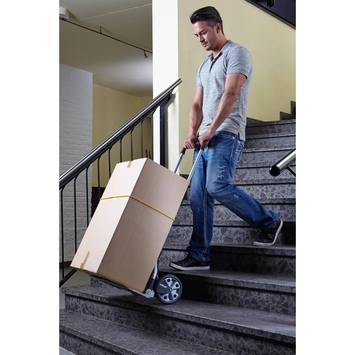 Mann transportiert Karton mit wolfcraft Sackkarre TS 850 auf Treppe.