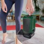 Person bedient grünen Bosch Akku-Bluetooth-Lautsprecher 18V-1 mit 18V-Akku auf Tisch. Ideal für kabelloses Streaming.