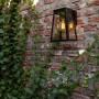 Anthrazitfarbene Lutec LED Solar-Wandleuchte Fia an Backsteinmauer mit Efeu.