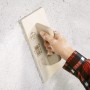 Hand mit LUX Schichtreibebrett zum Glätten einer Wand. Maurerwerkzeug mit Griff.