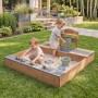 roba Sandkasten Teak mit Matschküche. Zwei Kinder spielen im Holz-Sandkasten mit Wasserhahn und Sitzbank.
