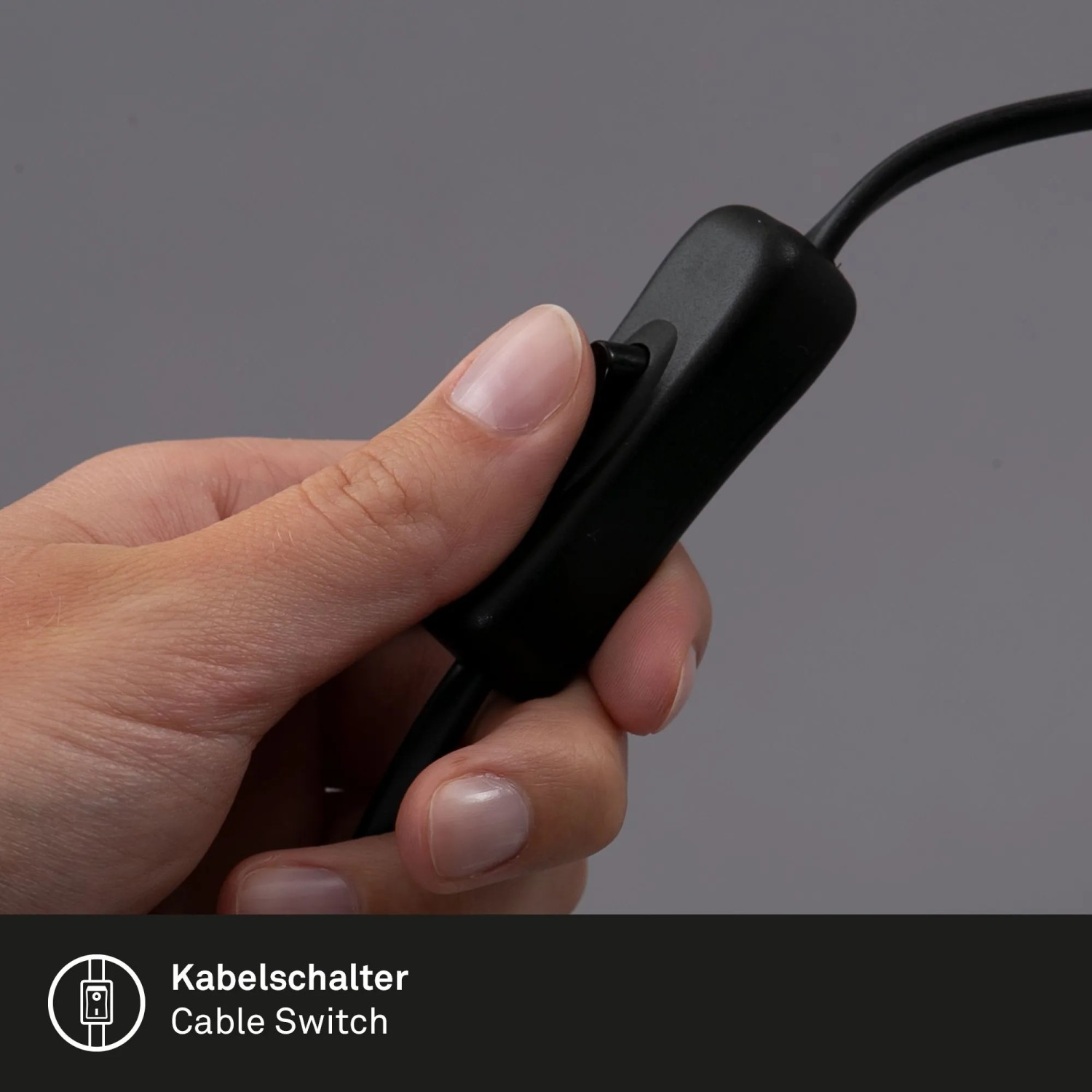 Detailaufnahme: Hand betätigt Kabelschalter der schwarzen Briloner Klemmleuchte.