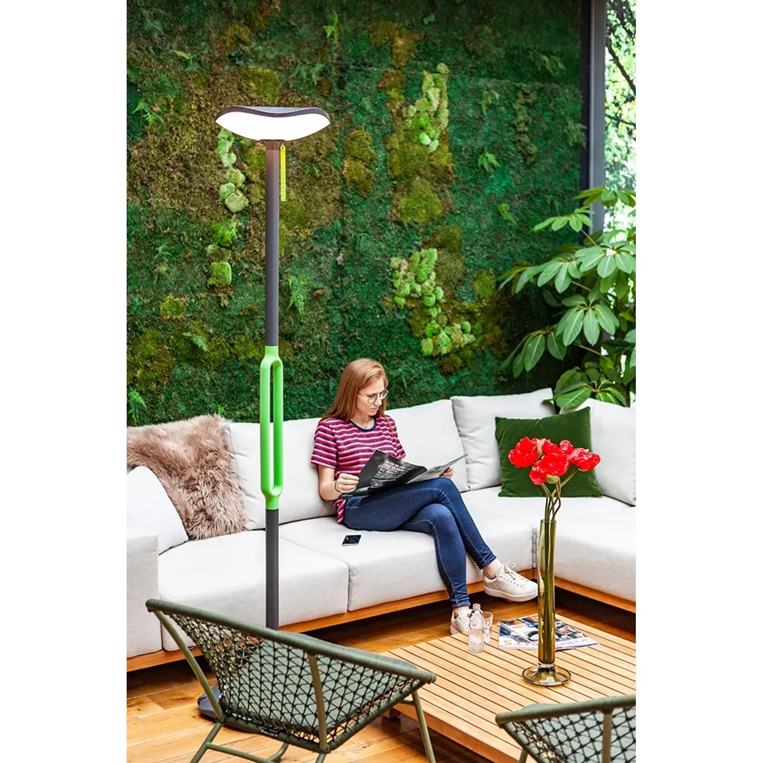 Lutec LED Solar Stehleuchte Poppy, anthrazit-grün, mit Frau auf Sofa im Hintergrund.