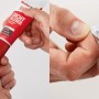 Fischer Dicht Kleber, 80ml Tube in roter Verpackung, wird von Hand geöffnet.