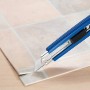 Blaues LUX Cuttermesser Classic 100 mm schneidet PVC-Bodenbelag auf Fliesenmuster Untergrund.