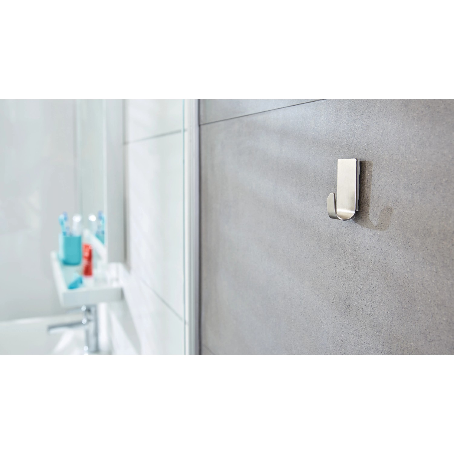 Tesa Powerstrips Haken Waterproof Zoom Edelstahl Small, 2er-Pack, an grauer Badezimmerwand.