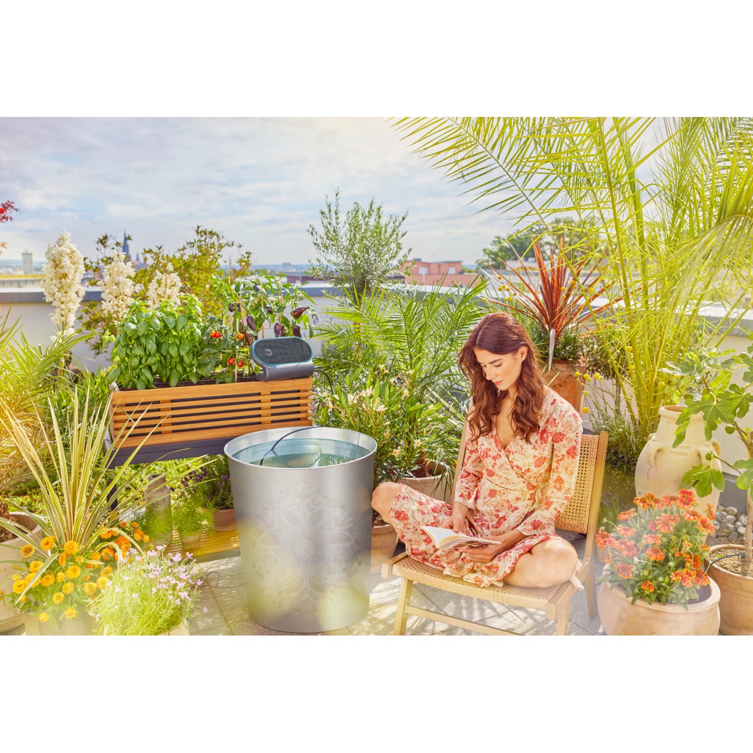 Gardena AquaBloom L Solar-Bewässerung auf Dachterrasse mit Pflanzen und Frau.