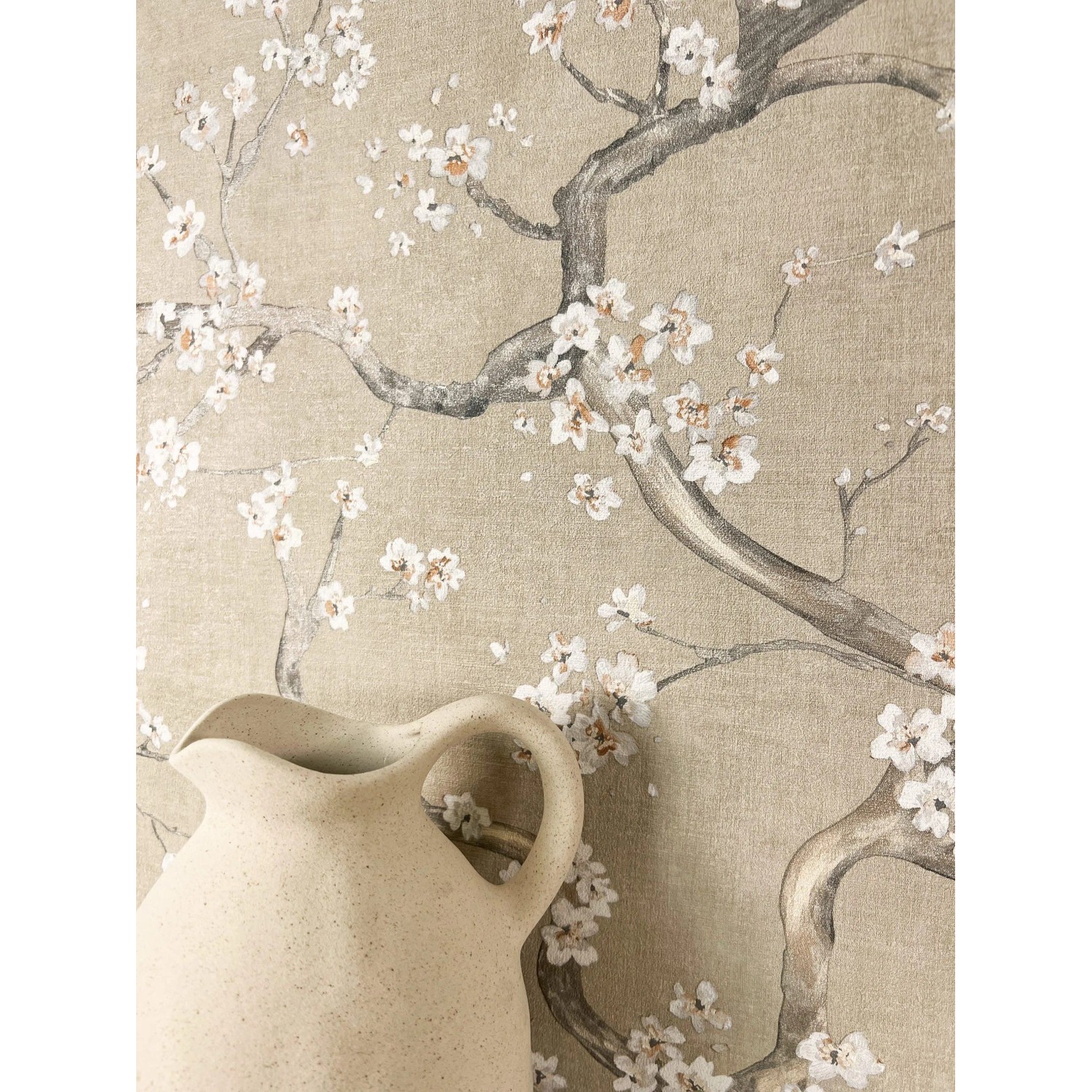 Beige Vliestapete mit weißen Kirschblüten und Ästen, ein Krug im Vordergrund. Dekorative Blumentapete für Wohnräume.