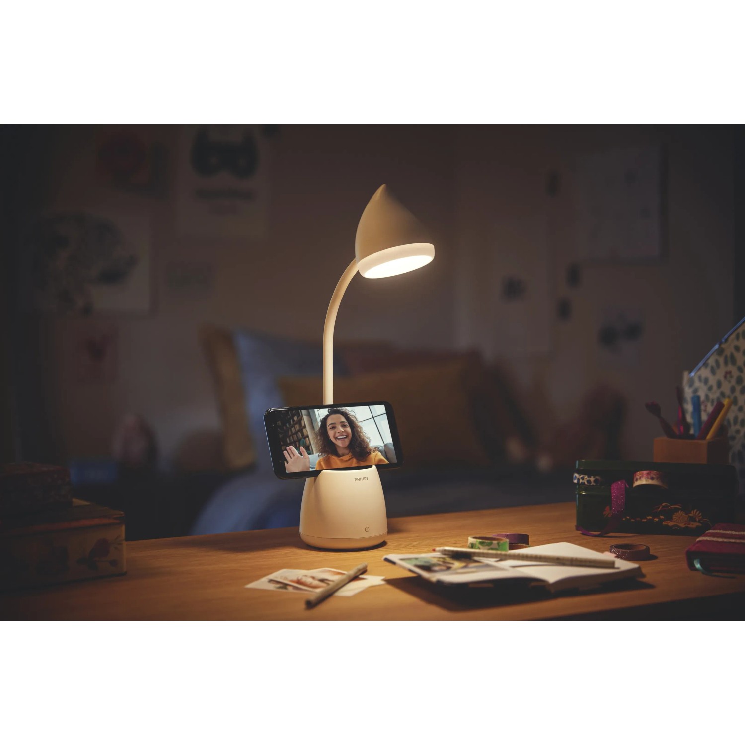 Weiße Philips LED Schreibtischleuchte Hat mit Handy im Stifthalter auf Schreibtisch.