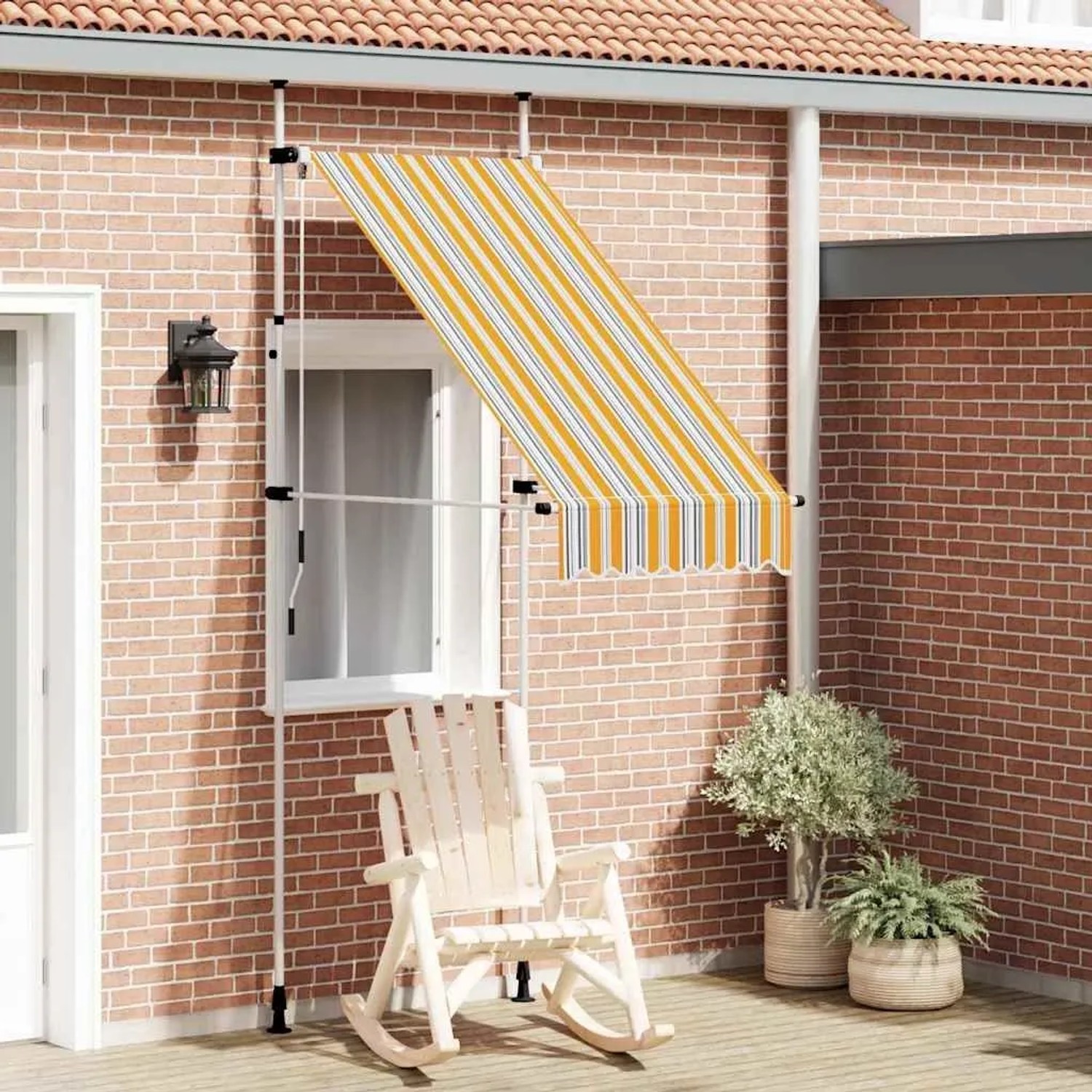 Gelb-blau gestreifte, handbetriebene Einziehmarkise an Ziegelwand über Fenster. Ideal als Schattenspender für Terrasse.