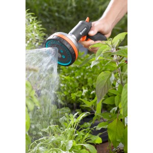 Gardena Premium Multibrause in Aktion: Hand hält Gartenspritze, Wasserstrahl bewässert Pflanzen.
