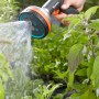 Gardena Premium Multibrause in Aktion: Hand hält Gartenspritze, Wasserstrahl bewässert Pflanzen.