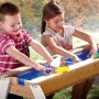 Kinder spielen am Axi Nick Sand- und Wasser-Picknicktisch aus Holz mit Sonnenschirm.