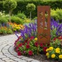 Gartenstecker aus Eisen in Rostoptik, 115 cm, mit "Grill + Chill Lounge" Schriftzug und Grill-Symbolen im Blumenbeet.