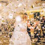 Goldener Sternenregen Konfetti fällt auf tanzendes Paar bei Hochzeit. Partypopper für Feiern.