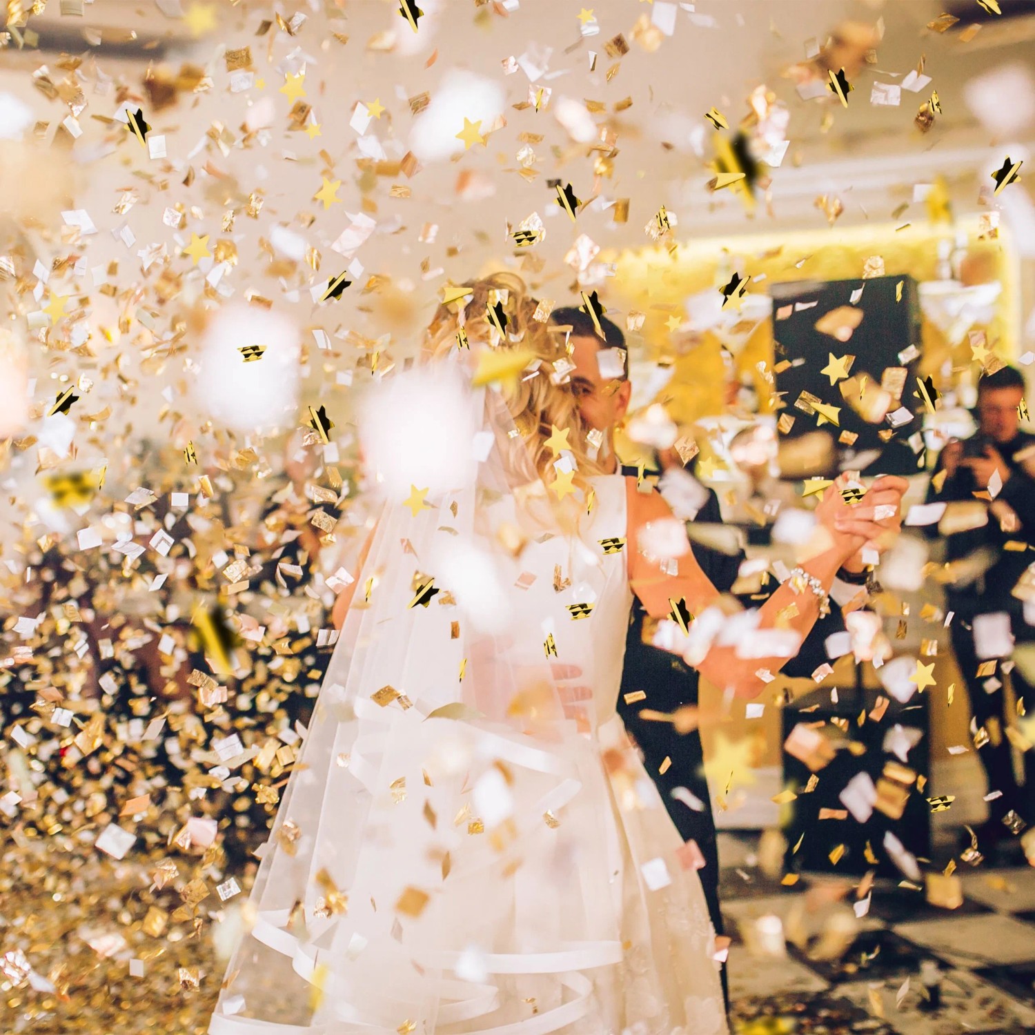 Goldener Sternenregen Konfetti fällt auf tanzendes Paar bei Hochzeit. Partypopper für Feiern.