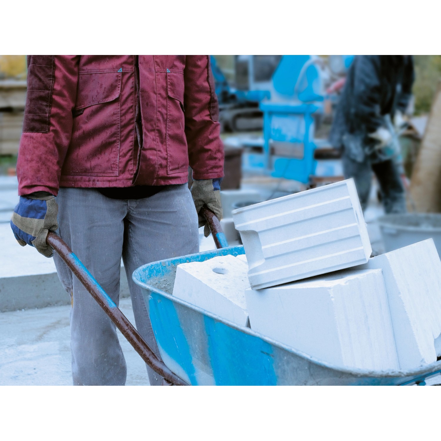 Mann mit LUX Winterarbeitshandschuhen Gr. 10 schiebt Schubkarre mit Steinen.