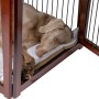 Großer, brauner Hundekäfig aus Holz mit Hund darin. Der Hund liegt auf einem Kissen im Hundezwinger.