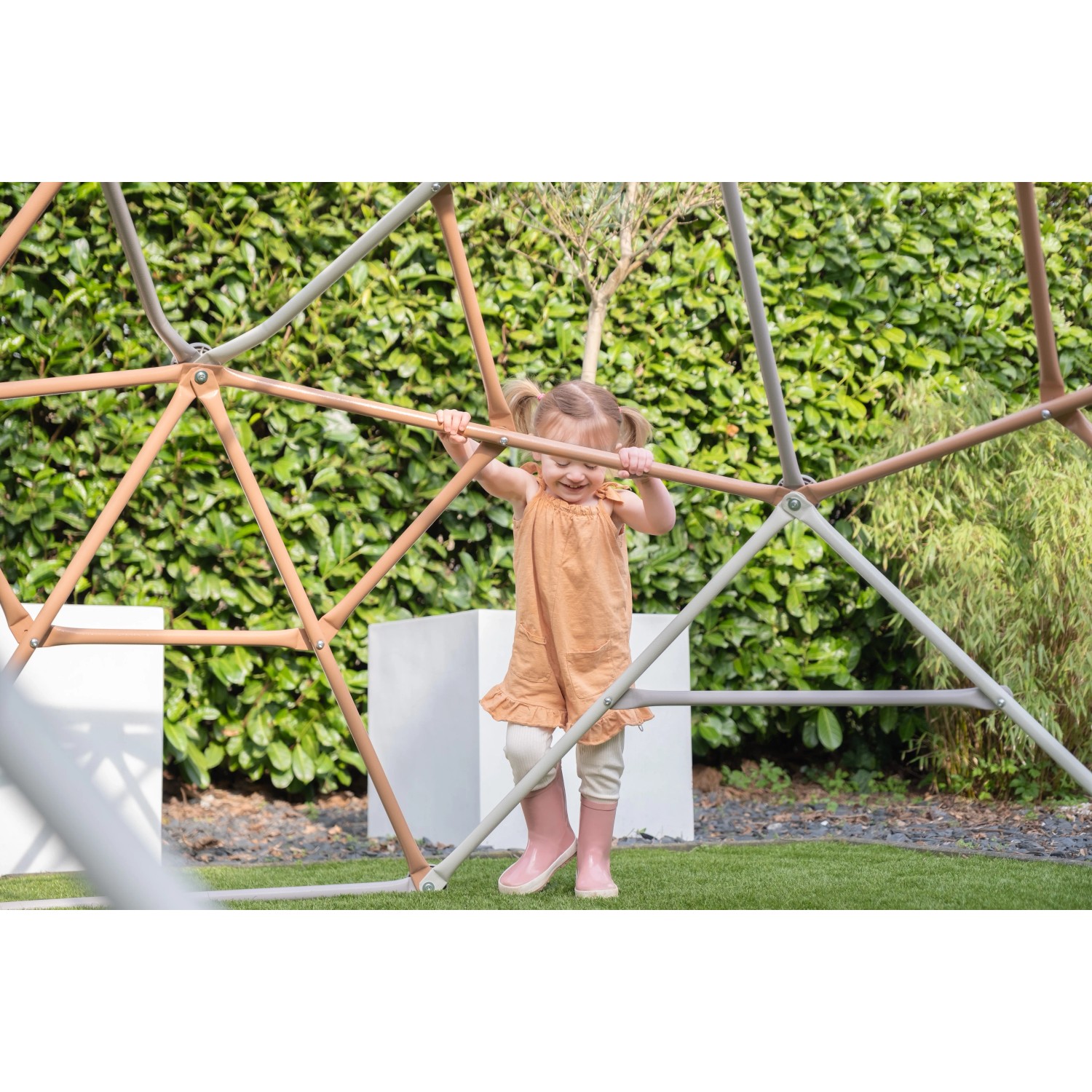 Kind klettert auf Exit Kletterkuppel Metal Climbing Dome (Ø 300 cm) im Garten.