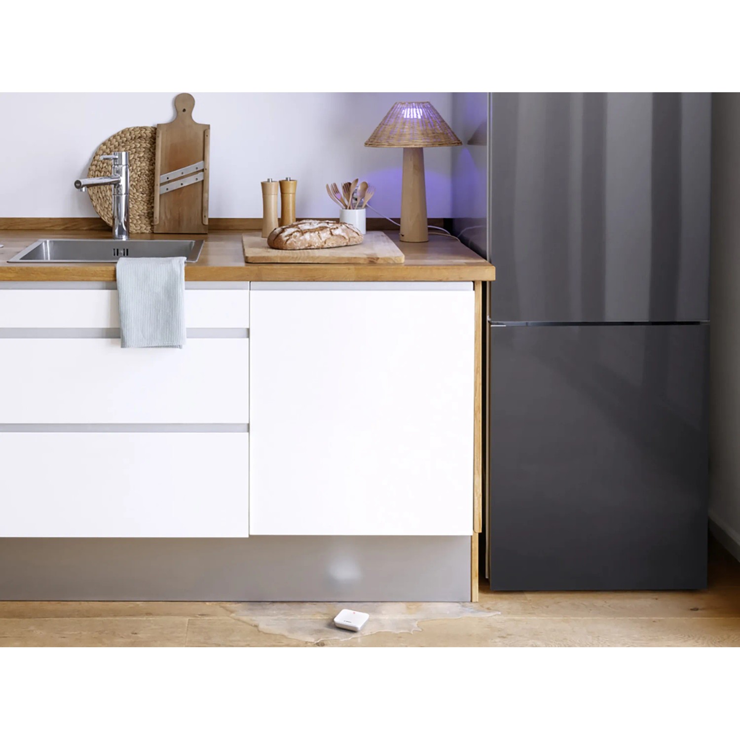 Bosch Smart Home Wassermelder BWA-1 im Einsatz unter Küchenzeile mit Wasseraustritt.