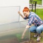 Transparentes Aluminium Frühbeet mit Frau beim Bepflanzen im Garten.