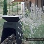 Schwarzer Vente-unique Grill Corvera aus Stahl mit Plancha und Holzfach, als Feuerstelle im Garten.