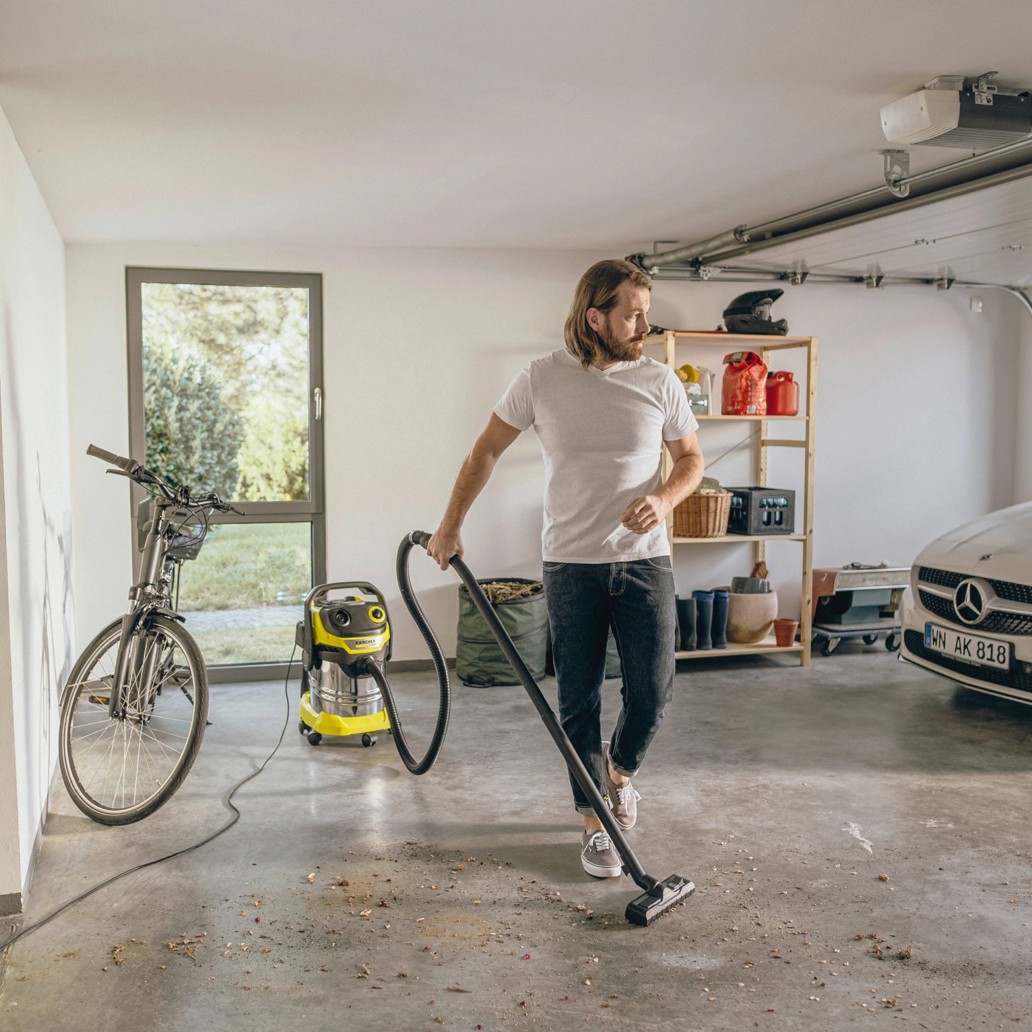 Mann saugt mit Kärcher WD 5 S V-25/5/22 Nass-/Trockensauger Garage. Edelstahlbehälter, gelb/schwarz.