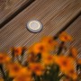 Runder Paulmann LED Bodeneinbaustrahler auf Holzterrasse mit Blumen, insektenfreundlich.