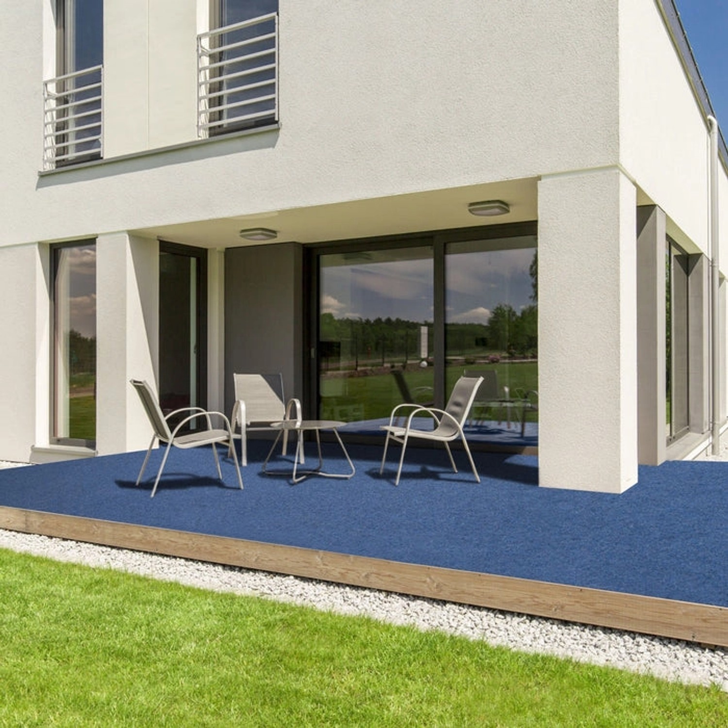 Blauer Karat Rasenteppich „Farbwunder PRO“ auf Terrasse mit Gartenmöbeln.