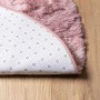 Rutschfeste Unterseite eines runden, altrosa Shaggy Hochflor Teppichs aus Polyester auf Holzfußboden.