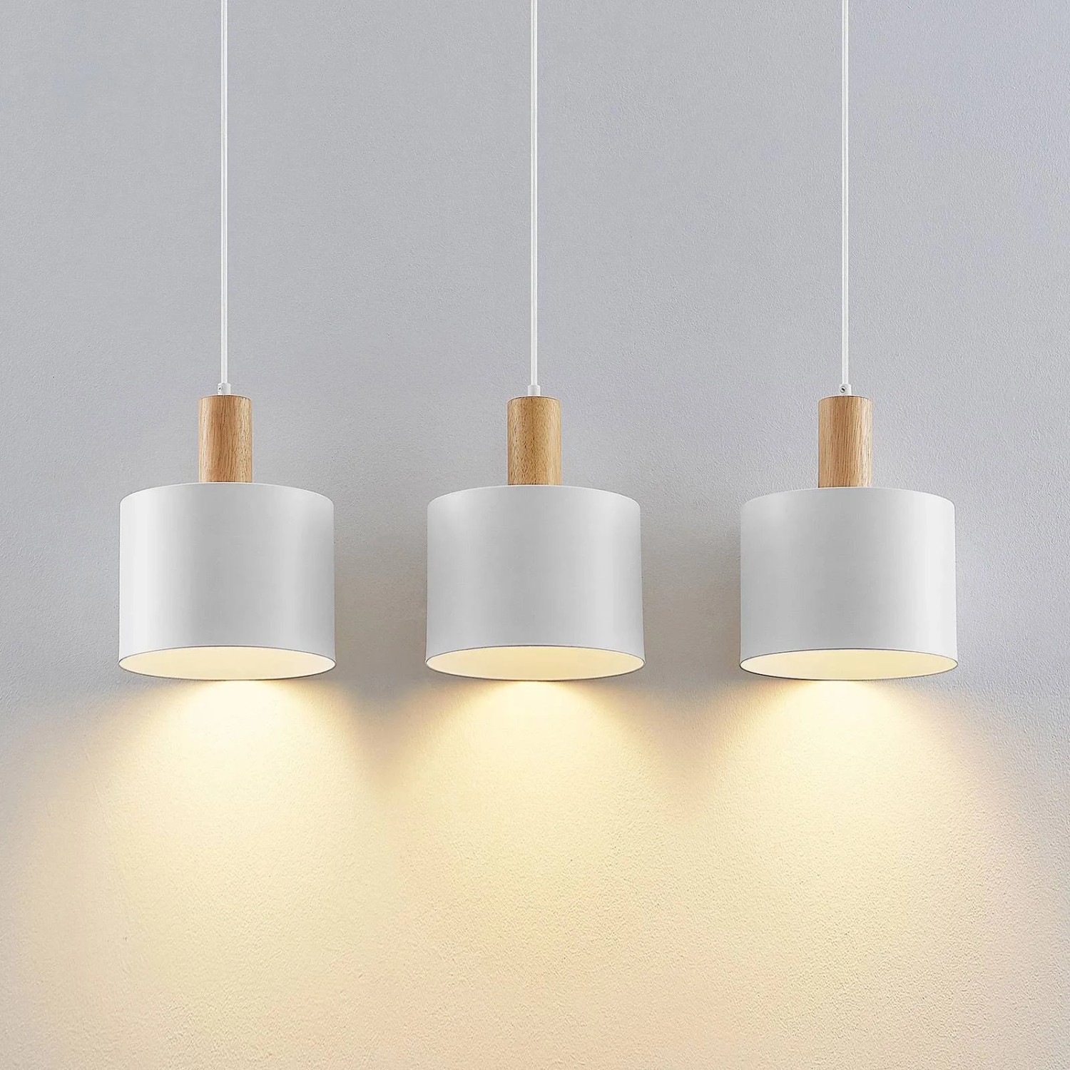 Drei moderne Lindby Kadir Pendelleuchten, weißes Metall mit Holzdetails, 3-flammig, warmes Licht. Ideal für Wohnzimmer.