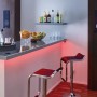 YourLED Lights & Sound Set von Paulmann: RGB LED-Streifen unter einer Bar mit Hockern.