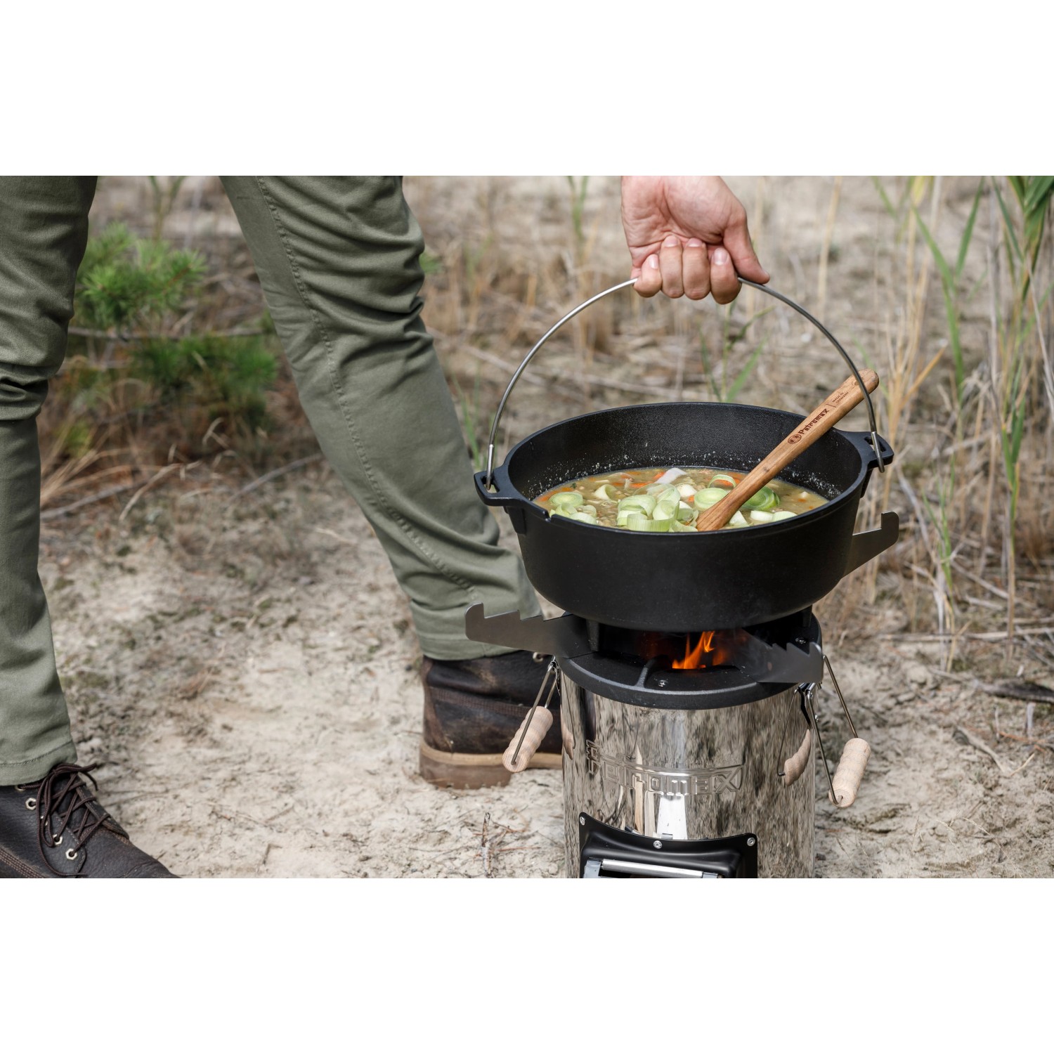 Petromax Raketenofen mit Grillplatte und Kochkreuz im Einsatz mit Dutch Oven. Grillutensil für Outdoor-Küche.