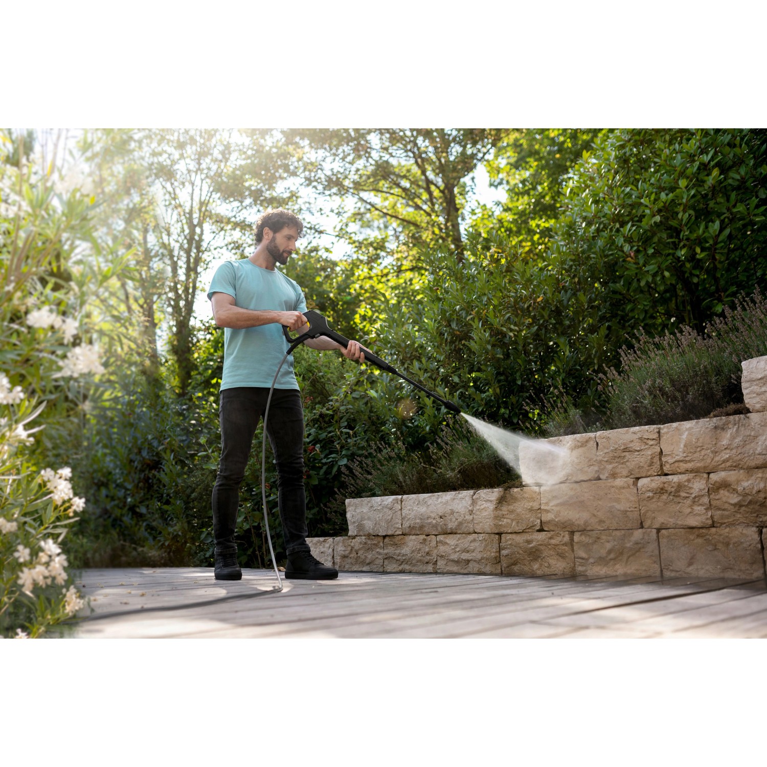 Mann reinigt Steinmauer mit Kärcher K 6 Flex Home Hochdruckreiniger im Garten.