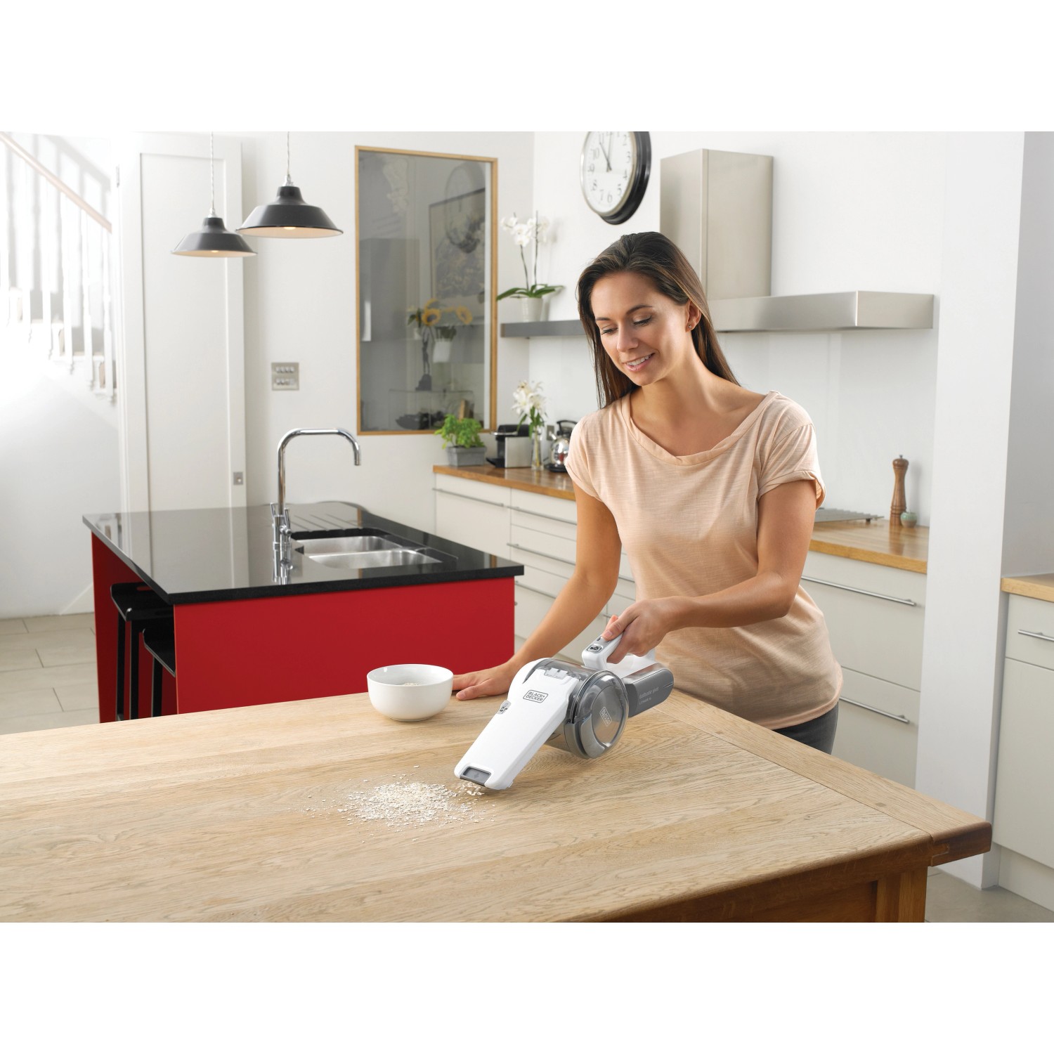Frau saugt Krümel mit dem Black+Decker Akku-Handstaubsauger Dustbuster Pivot PV1820L vom Tisch.