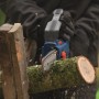 Bosch Akku-Astsäge GKE 18V-15 in Aktion: Bediener sägt Ast mit Akku-Kettensäge im Garten.